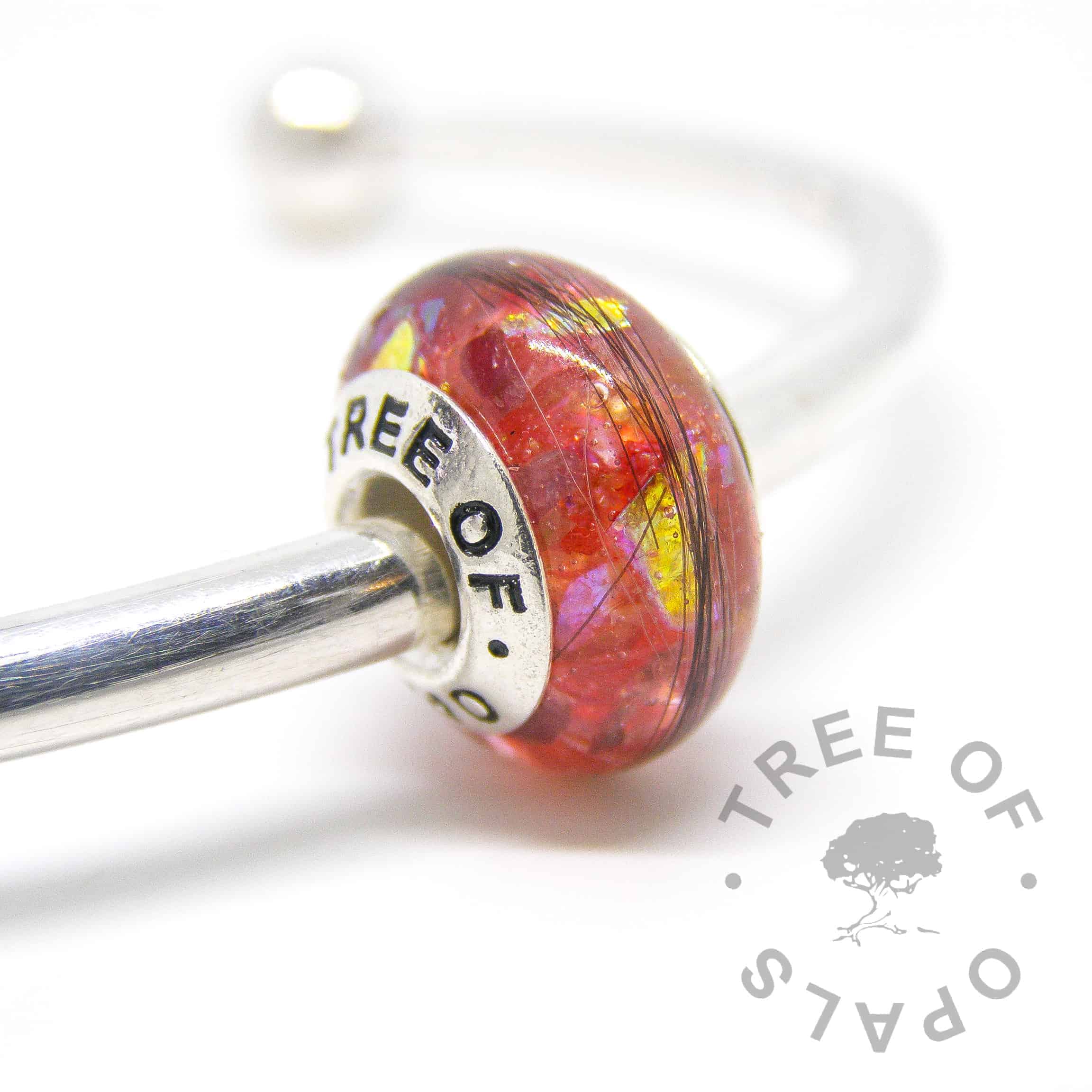 lock of hair charm bead in resin, ruby July birthstone, red opalescent flakes and genuine gold leaf guilded centre with a solid sterling silver Tree of Opals branded core