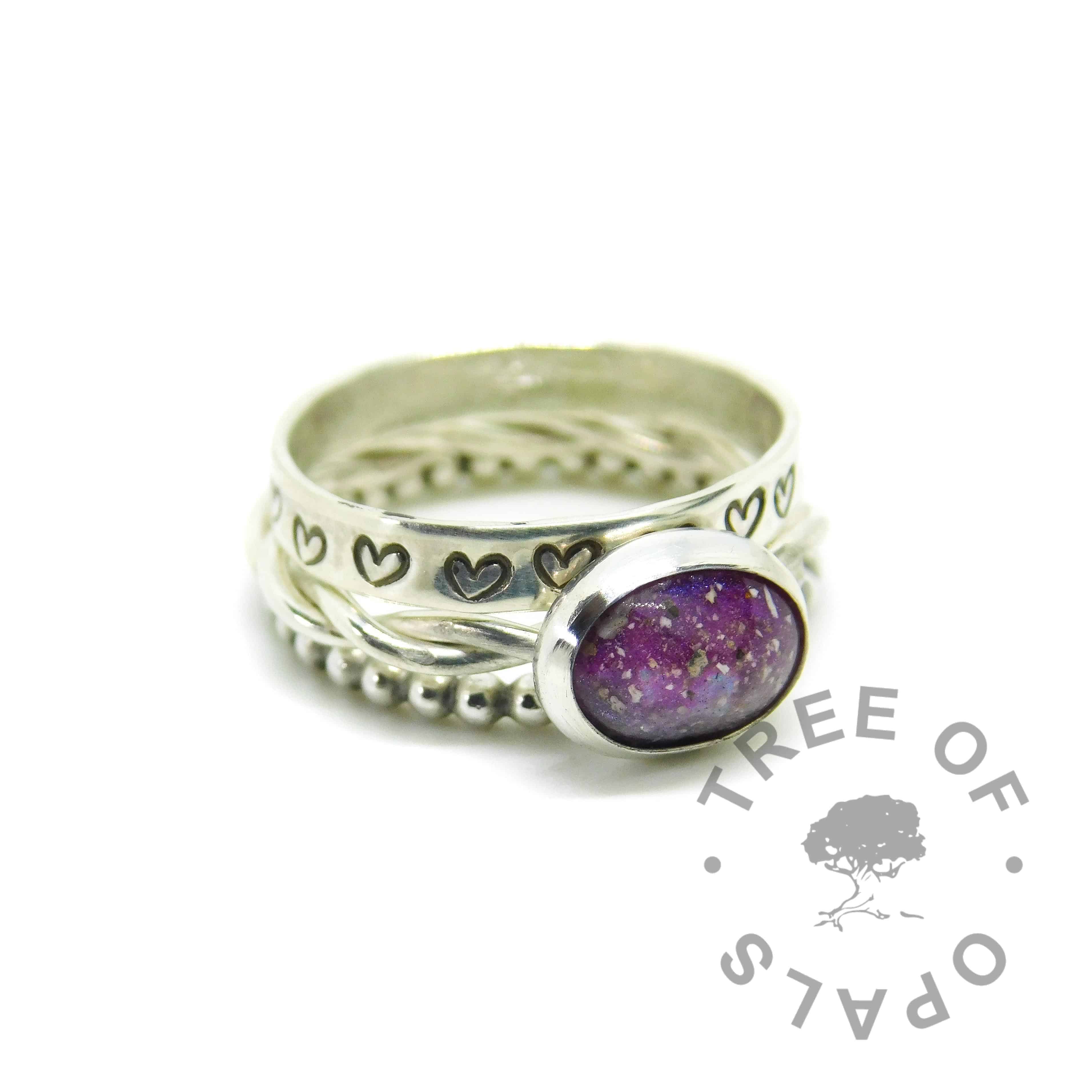 cremation ash ring with orchid purple and fairy pink resin sparkle mixes swirled together, no birthstone. Handmade twisted band EcoSilver ring shank, 10x8mm bezel cup. Shown with heart stamped and bubble wire stacking rings. Watermarked copyright Tree of Opals memorial jewellery image