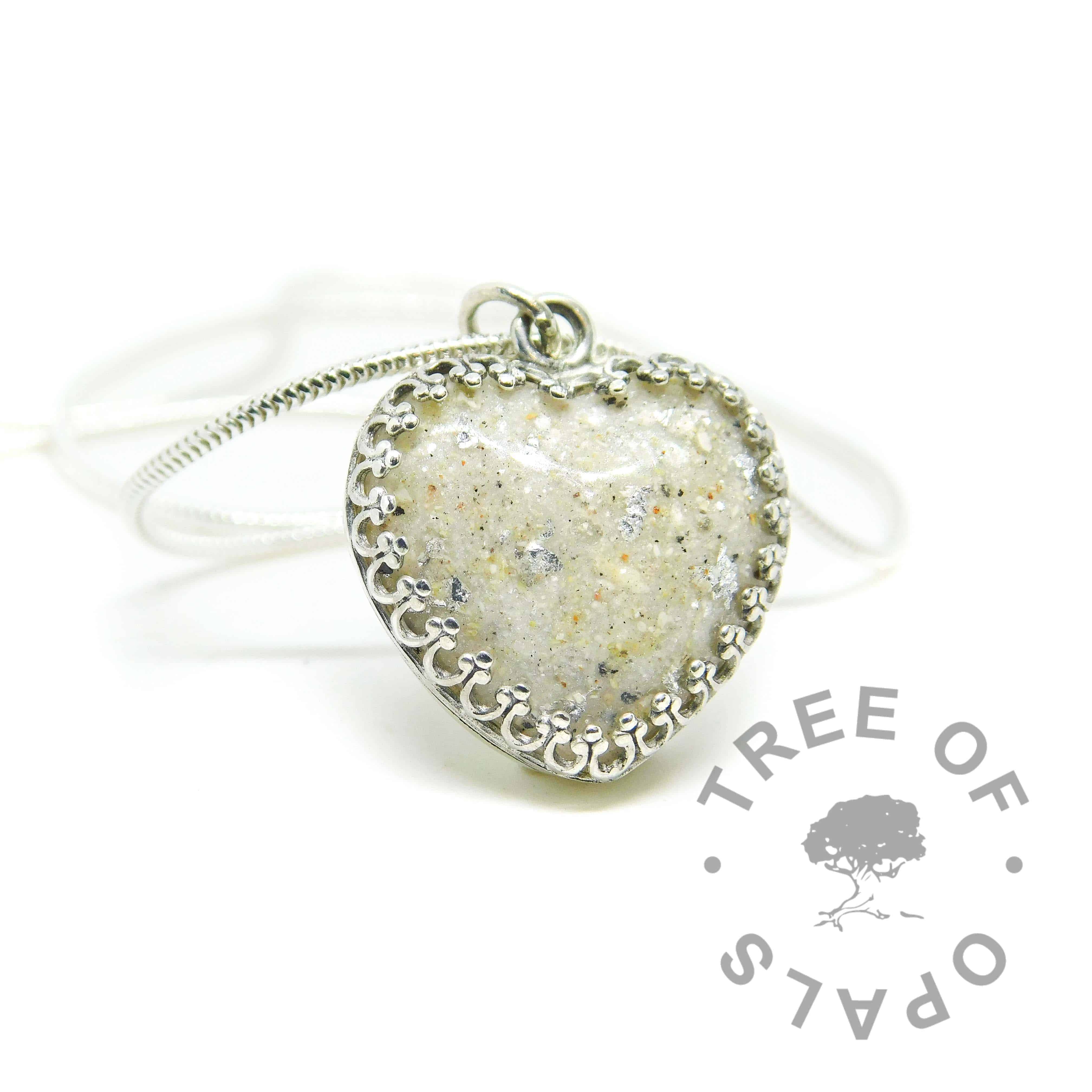 Cremation ash heart necklace with unicorn white resin sparkle mix, naturally dark ashes, silver leaf and no birthstone. Solid sterling silver 20mm crown point heart setting (925 stamped on the back). Lightweight snake chain necklace upgrade shown (sold separately). Watermarked copyright Tree of Opals memorial jewellery image