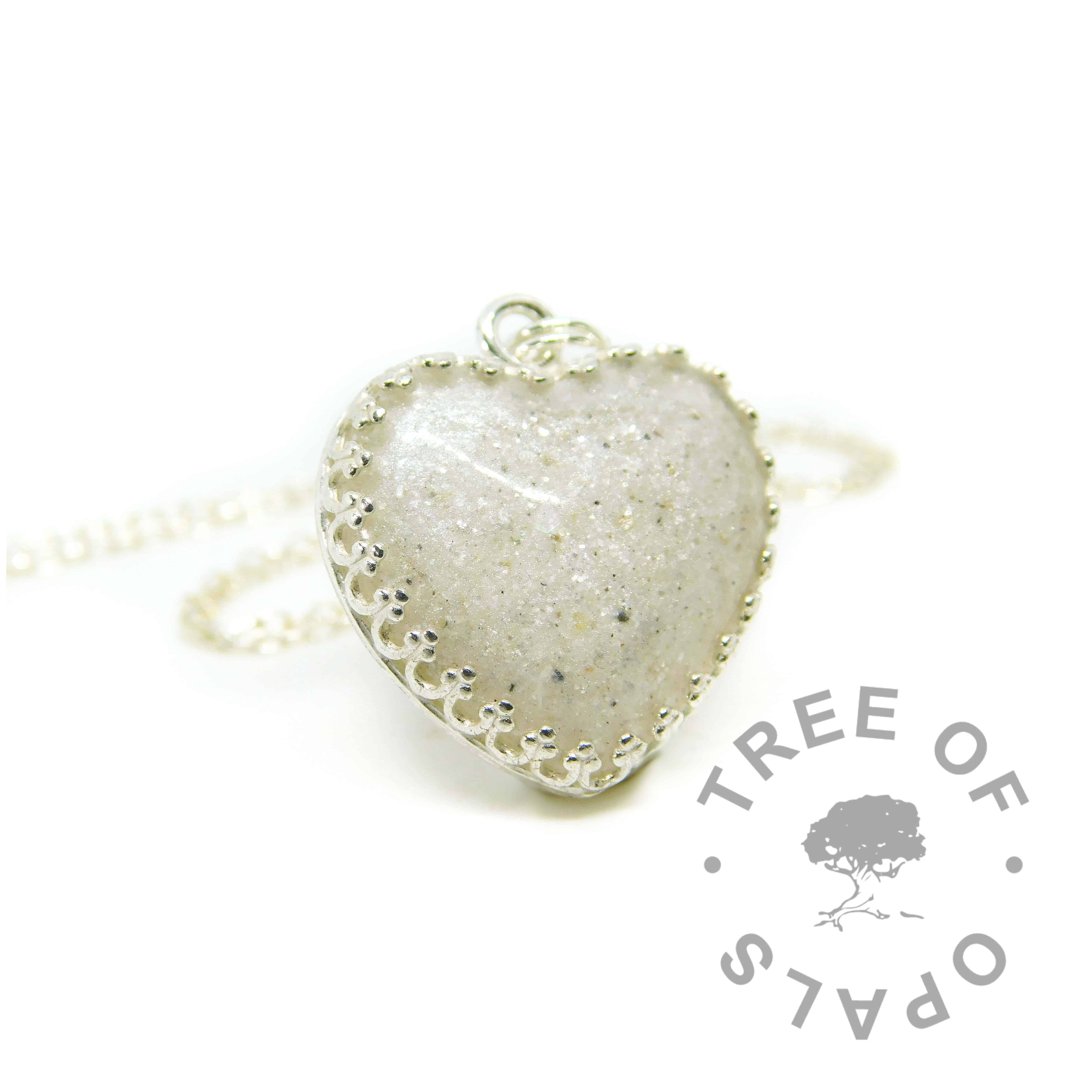 Cremation ashes with crystal clear resin, set in an 18mm heart cabochon with unicorn white resin sparkle mix, in a solid sterling silver crown setting. Shown on standard chain. Watermarked copyright image by Tree of Opals