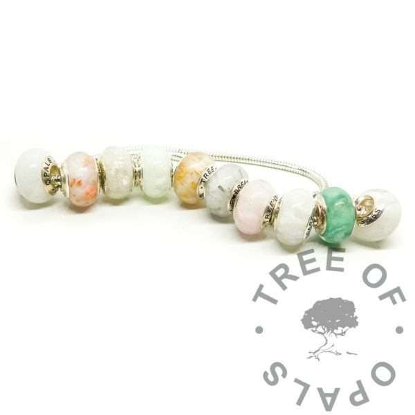 breastmilk beads on snake chain necklace. Breastmilk beads set of ten boobie awards. Left to right: 1. classic breastmilk 2. breastmilk with copper leaf for three month boobie award 3. breastmilk with silver leaf for six month boobs 4. breastmilk and jade resin sparkles subtle green pearlescent with a little angelic aqua for nine month nursiversary 5. breastmilk with gold leaf for one year breastfeeding milestone 6. milk bead with platinum leaf for eighteen month boobies 7. breastmilk and pearlescent pink with a touch of fairy pink for faux morganite to represent breastfeeding a baby with allergies, for example CMPA 8. breastmilk with moonstone effect, purple and blue pearlescent powders and indigo clear opalescent flakes to represent receiving donor milk boobie award 9. faux emerald with amazon jungle green ethically sourced mica and green pearlescent powder for the exclusively pumping breastfeeding award 10. breastmilk with genuine diamond powder